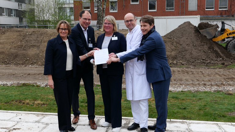 Hamburgs Sozialsenatorin Melanie Schlotzhauer, Amalie-Geschäftsführer Andreas Schneider, Pflegedirektorin Maike Sellentin, der Ärztliche Direktor Prof. Dr. Ernst von Dobschütz und der Konzerngeschäftsführer der Immanuel Albertinen Diakonie Dr. Thorsten Minuth (von links) halten symbolisch den Fördermittelbescheid über 53 Millionen Euro für den Neubau am Evangelischen Amalie Sieveking Krankenhaus in Hamburg-Volksdorf in die Kamera. Hamburgs Sozialsenatorin Melanie Schlotzhauer, Amalie-Geschäftsführer Andreas Schneider, Pflegedirektorin Maike Sellentin, der Ärztliche Direktor Prof. Dr. Ernst von Dobschütz und der Konzerngeschäftsführer der Immanuel Albertinen Diakonie Dr. Thorsten Minuth (von links) halten symbolisch den Fördermittelbescheid über 53 Millionen Euro für den Neubau am Evangelischen Amalie Sieveking Krankenhaus in Hamburg-Volksdorf in die Kamera.