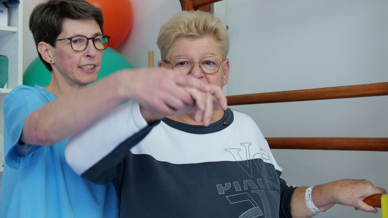 Ergotherapeutin begleitet Patientin bei Übung