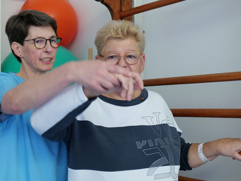 Ergotherapeutin begleitet Patientin bei Übung