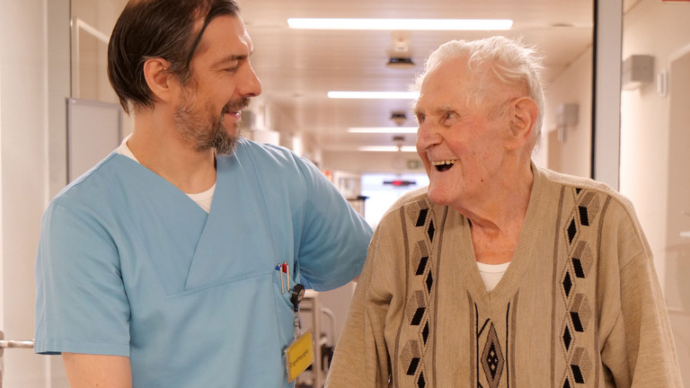 Pfleger begleitet Patienten mit Rollator Pfleger begleitet Patienten mit Rollator