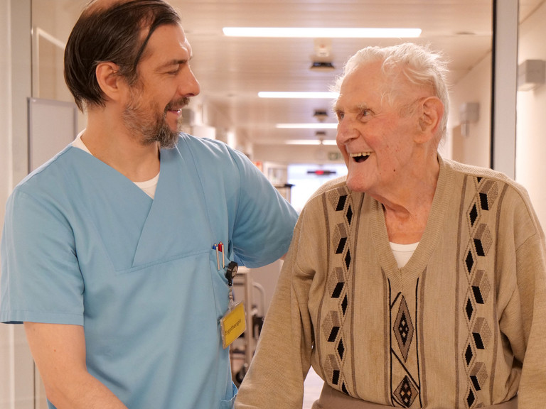 Pfleger begleitet Patienten mit Rollator Pfleger begleitet Patienten mit Rollator