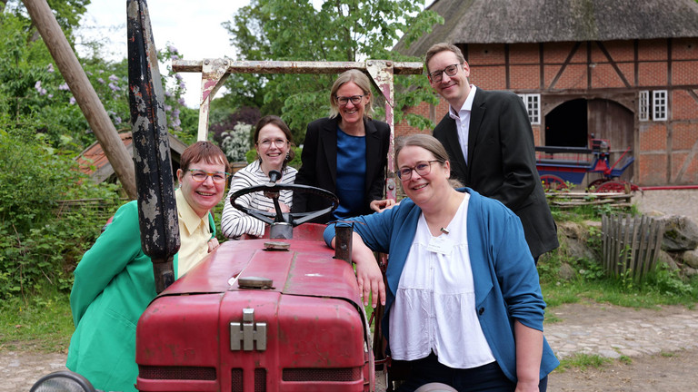 r. Saskia Otte mit Kolleginnen und Kollegen beim Einführungssymposium im Museumsdorf Volksdorf vor einem historischen Traktor.