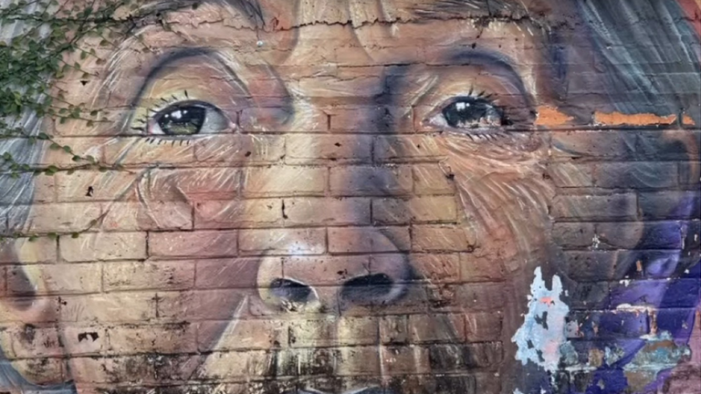 Wandgraffiti mit dem Gesicht einer älteren Frau in El Salvador zur Veranstaltung Altersmedizin neu gedacht – Perspektiven der  „Jungen Geriatrie - Fachsymposium Einführung Dr. med. Saskia Otte im Evangelischen Amalie Sieveking Krankenhaus in Hamburg