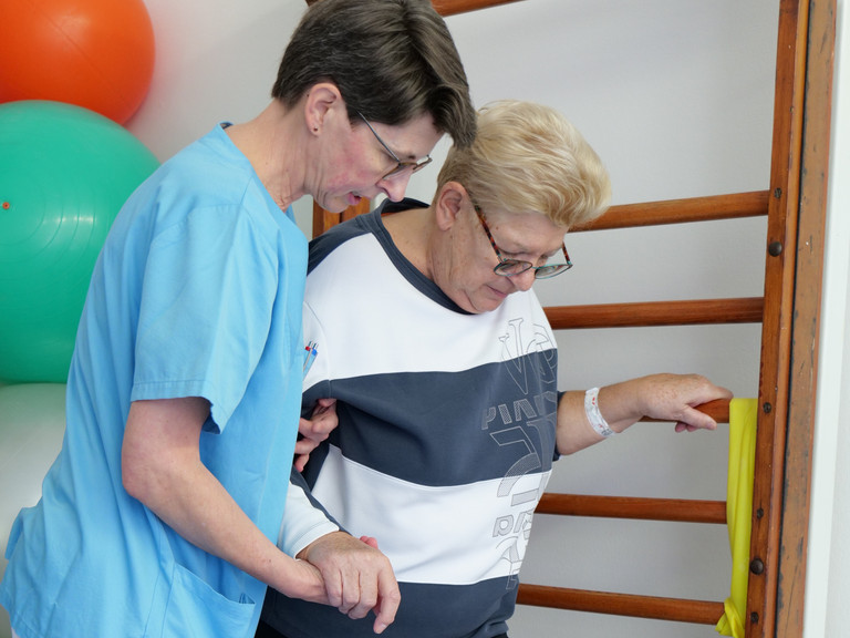 Eine Physiotherapeutin unterstützt eine Patientin während einer Übung im Amalie Alterstraunazentrum