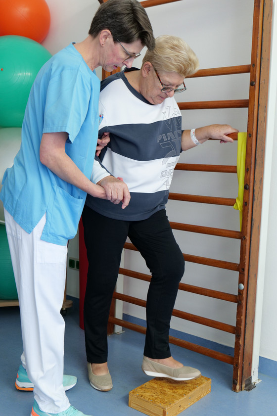 Eine Physiotherapeutin unterstützt eine Patientin während einer Übung im Amalie Alterstraunazentrum