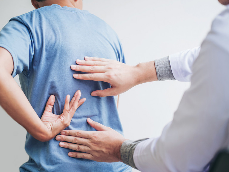 Arzt tastet den Rücken eines Patienten ab - Evangelisches Amalie Sieveking Krankenhaus Hamburg - Bandscheibenvorfall Behandlung