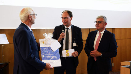 Geschenkübergabe auf der Bühne an Dr. Michael Musolf bei dessen Verabschiedung in den Ruhestand, Chefarzt der Klinik für Geriatrie und Physikalische Medizin im Evangelischen Amalie Sieveking Krankenhaus