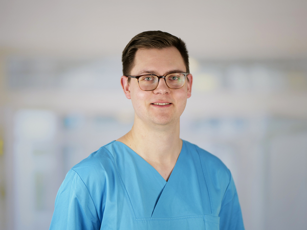 Portraitfoto von René Siebenborn, Pflegerischer Abteilungsleiter der Anästhesiologie und Intensivmedizin im Evangelischen Amalie Sieveking Krankenhaus in Hamburg, in blauer Funktionskleidung.