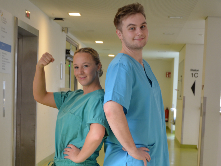  Zwei Pflegefachkräfte Rücken an Rücken in einem Krankenhausgang im Evangelischen Amalie Sieveking Krankenhaus