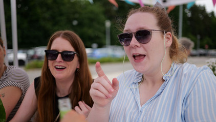Zwei Mitarbeiterinnen sitzen mit Sonnenbrillen an einem Tisch beim Sommerfest 2026 auf dem Gesundheitscampus Volksdorf vom Evangelischen Amalie Sieveking Krankenhaus, Residenz am Wiesenkamp, Feierabendhaus Volksdorf und Albertinen Kindertagesstätte Volksdorf. 