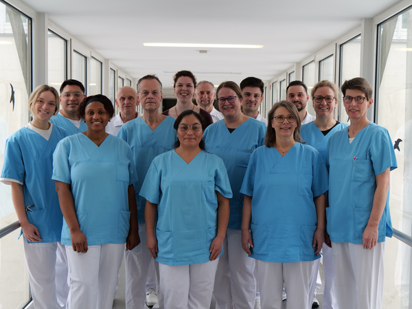 Das Team des Amalie Alterstraumazentrum blickt in Dienstkleidung auf einem krankenhausflur in die Kamera