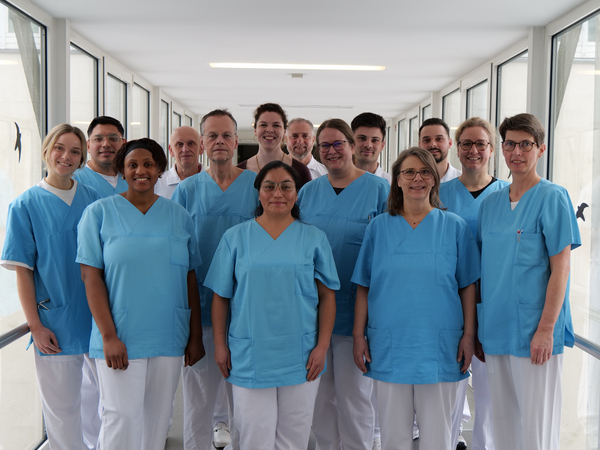 Das Team des Amalie Alterstraumazentrum blickt in Dienstkleidung auf einem krankenhausflur in die Kamera