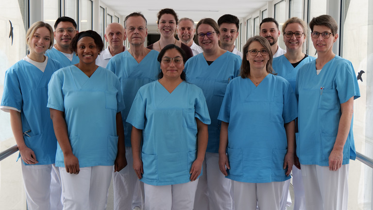 Das Team des Amalie Alterstraumazentrum blickt in Dienstkleidung auf einem krankenhausflur in die Kamera