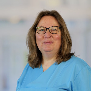 Portraitfoto von Birgit Petersen, Sekretariat Gynäkologie und Urogynäkologie im Evangelischen Amalie Sieveking Krankenhaus in Hamburg-Volksdorf, in blauer Funktionskleidung.