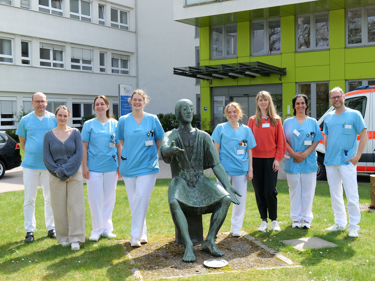 Mehrere neue Ärztinnen stehen mit Prof. von Dobschütz, dem Ärztlichen Direktor, sowie Prof. Matthias Grünewald, Chefarzt Anästhesie und Intensivmedizin, für ein Gruppenfoto vor dem Amalie Sieveking Krankenhaus mit einer Bronzefigur von Amalie Wilhelmine Sieveking beim Einführungstag für neue Ärztinnen und Ärzte.
