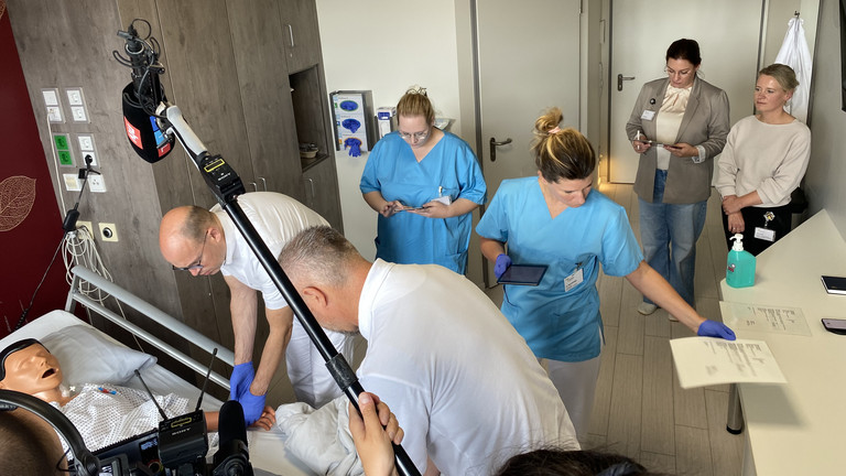 Der Ärztliche Direktor Prof. Dr. med. Ernst von Dobschütz und ein Pflegeteam stehen an einem Pflegebett mit einer Übungspuppe bei der Übung zur Patientensicherheit Room of Horrors mit TV-Begleitung im Amalie Sieveking Krankenhaus in Hamburg-Volksdorf