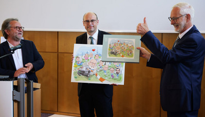 Übergabe einer Zeichung auf der Bühne an Dr. Michael Musolf bei dessen Verabschiedung in den Ruhestand, Chefarzt der Klinik für Geriatrie und Physikalische Medizin im Evangelischen Amalie Sieveking Krankenhaus