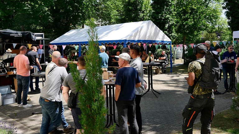 Menschen an Stehtischen im Hof Menschen an Stehtischen im Hof