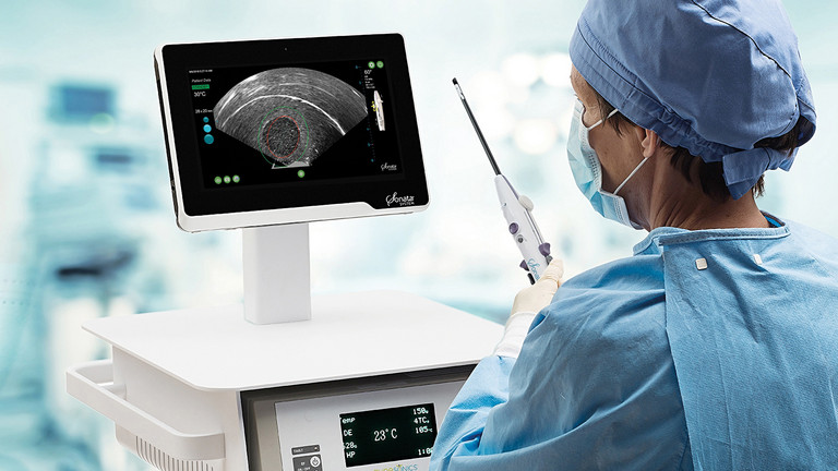 Eine ärztliche Person in OP Kleidung schaut auf einen Ultraschallbildschirm und hält das Sonata® System in der Hand