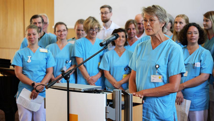  Mitarbeitende in Fuktionskleidung auf der Bühne bei Verabschiedung Dr. Michael Musolf in den Ruhestand, Chefarzt der Klinik für Geriatrie und Physikalische Medizin im Evangelischen Amalie Sieveking Krankenhaus