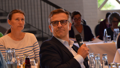 Ein Teilnehmer spricht am Tisch mit Handmikrofon beim 10. Amalie Tag der Hausärztinnen und -ärzte im Evangelischen Amalie Sieveking Krankenhaus in Hamburg-Volksdorf
