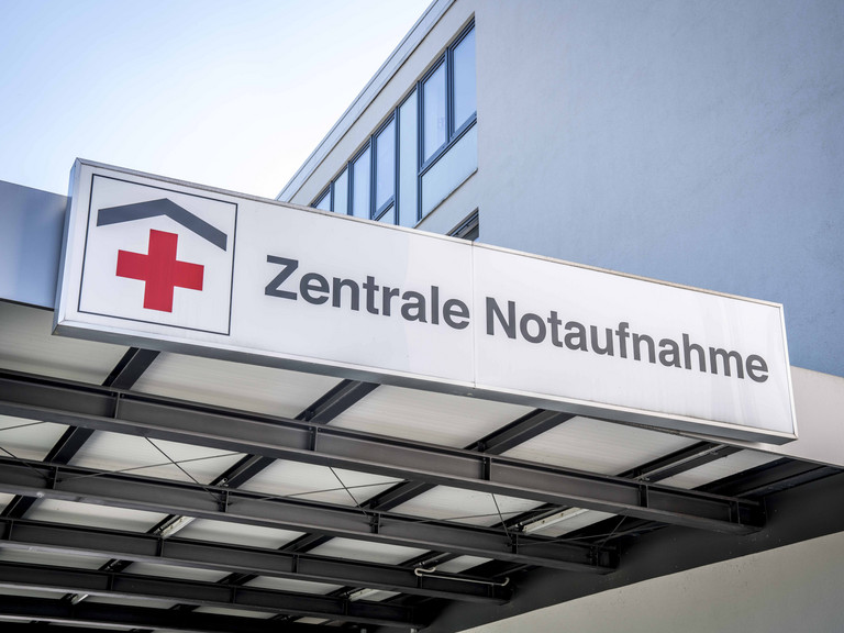 Eine breites weißes Schild mit der Aufschrift Zentrale Notaufnahme und einem roten Kreuz-Logo über dem Eingang zur Zentralen Notaufnahme des Evangelischen Amalie Sieveking Krankenhauses in Hamburg-Volksdorf