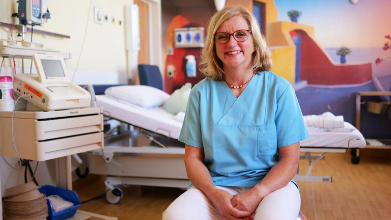Kerstin Stehr-Archuth, Leitende Hebamme im Evangelischen Amalie Sieveking Krankenhaus, sitzt in einem Kreißsaal und blickt in die Kamera, babyfreundliche Geburt, WHO, UNICEF, Stillen, Bonding, Hamburg-Volksdorf Kerstin Stehr-Archuth, Leitende Hebamme im Evangelischen Amalie Sieveking Krankenhaus, sitzt in einem Kreißsaal und blickt in die Kamera