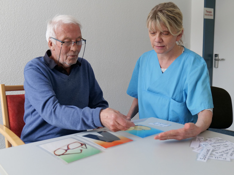 Patient und Therapeutin bei einer Übung mit großen Karten - Evangelisches Amalie Sieveking Krankenhaus Hamburg  - Demenz Behandlung