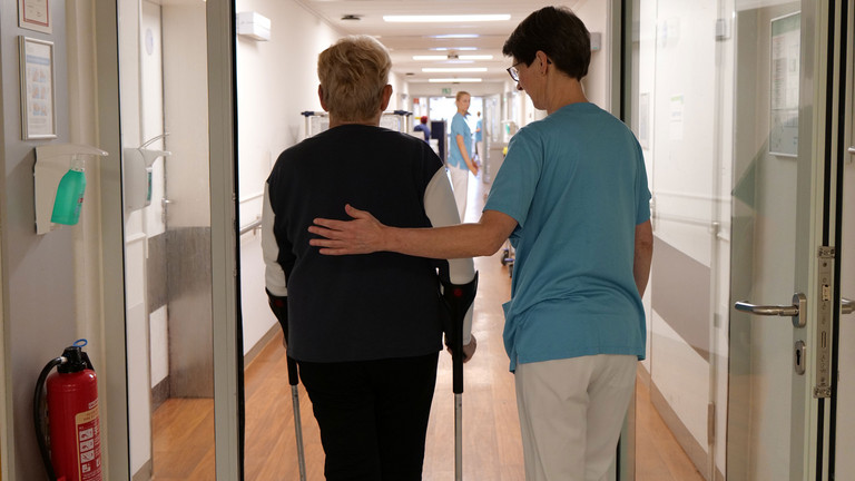 Therapeutin begleitet Patientin mit Krücken