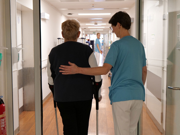 Therapeutin begleitet Patientin mit Krücken Therapeutin begleitet Patientin mit Krücken
