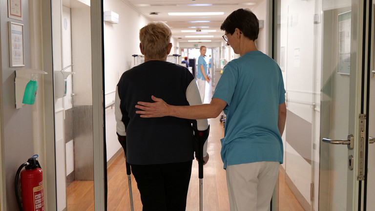 Therapeutin begleitet Patientin mit Krücken