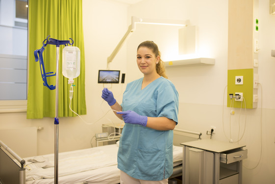 Auf dem Foto sieht man eine Pflegefachfrau in einem Patienten-Zimmer Auf dem Foto sieht man eine Pflegefachfrau in einem Patienten-Zimmer