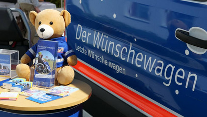 Ein Teddy auf einem Infotisch vor dem Wünschewagen am Tag der Begegnungen des Albertinen Hospiz Norderstedt